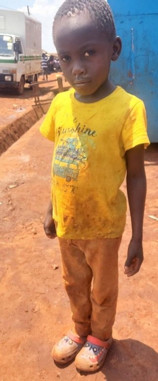 Paul in verschmutzter Kleidung auf einer Sandstraße in den Slums.